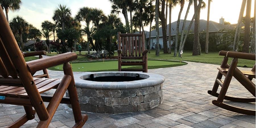 Firepit and pavers with some chairs surrounding it by Brevard Outdoor Services